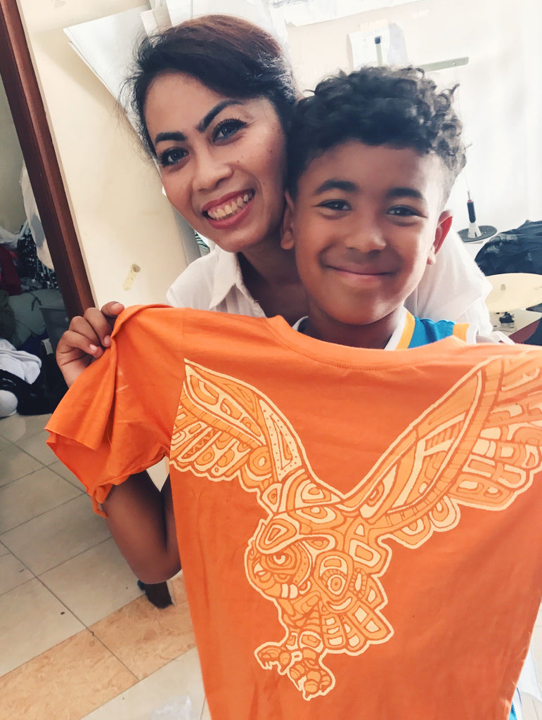 Production manager Arti, with Andreas PEACE FITS owner’s son, Sadiki. At Arti Bali, a family-owned factory.  Sadiki is holding one of our older kids tees with original Owl graphic from the “EarthTRiBE” collection